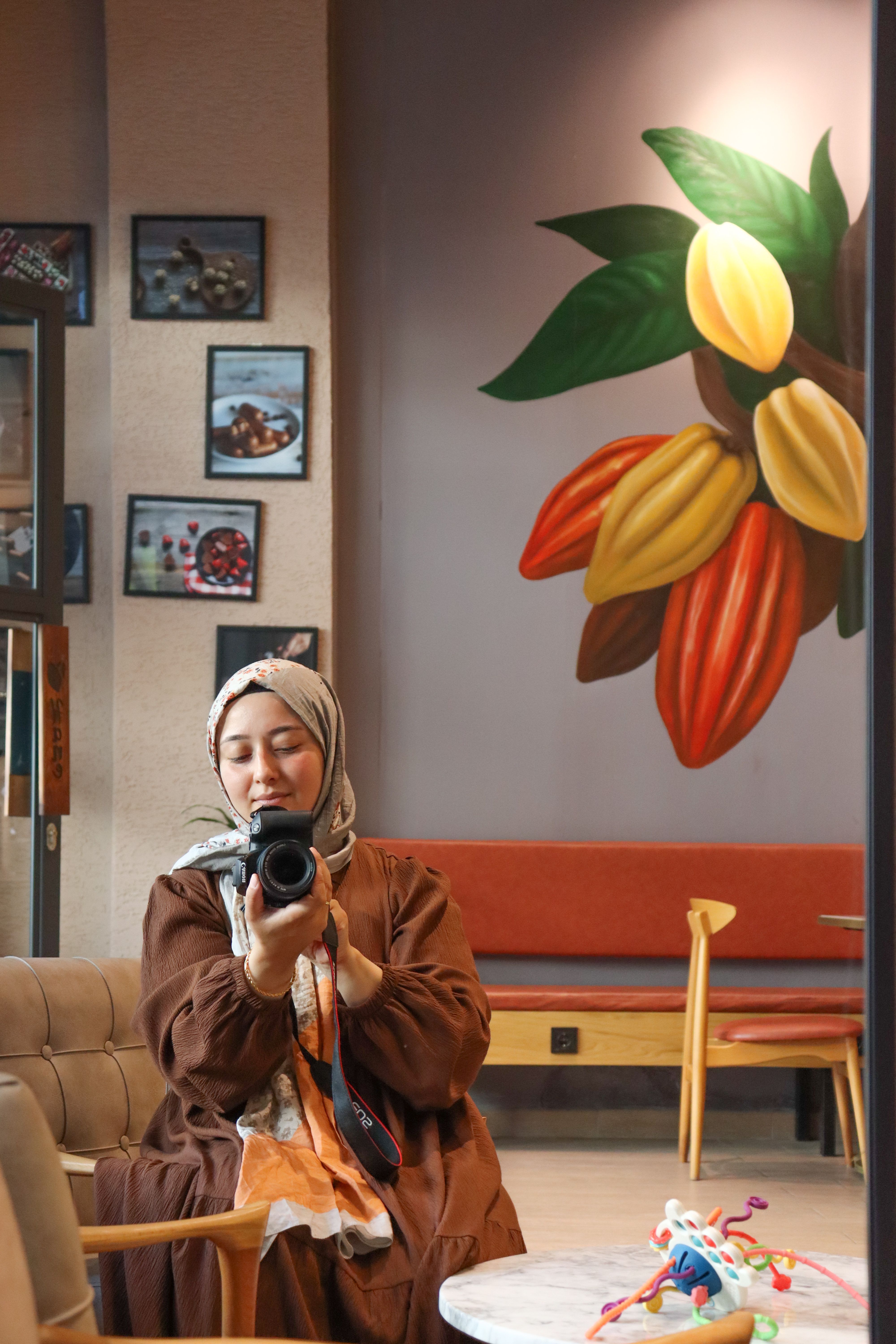 A woman captures a self-portrait in a cozy cafe with colorful decor.
