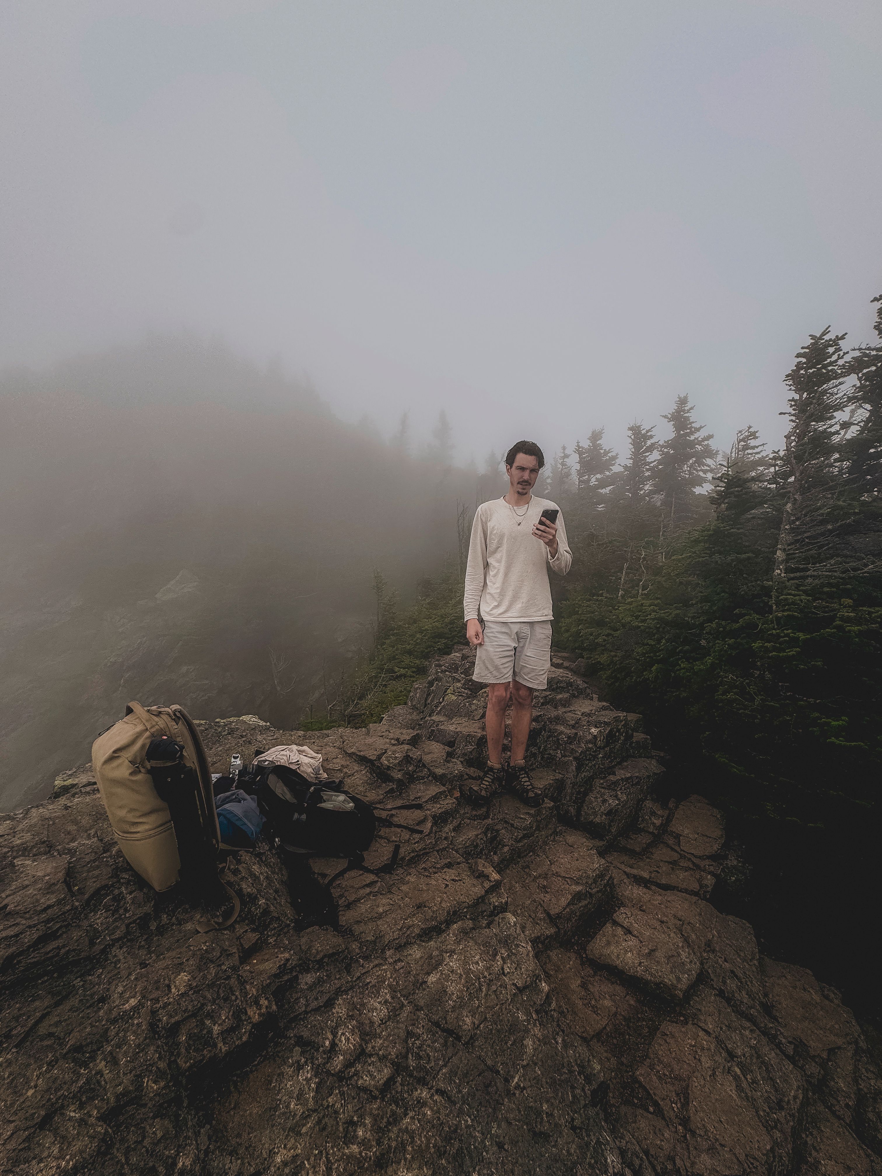 A man standing on top of a mountain with a backpack · Free Stock Photo