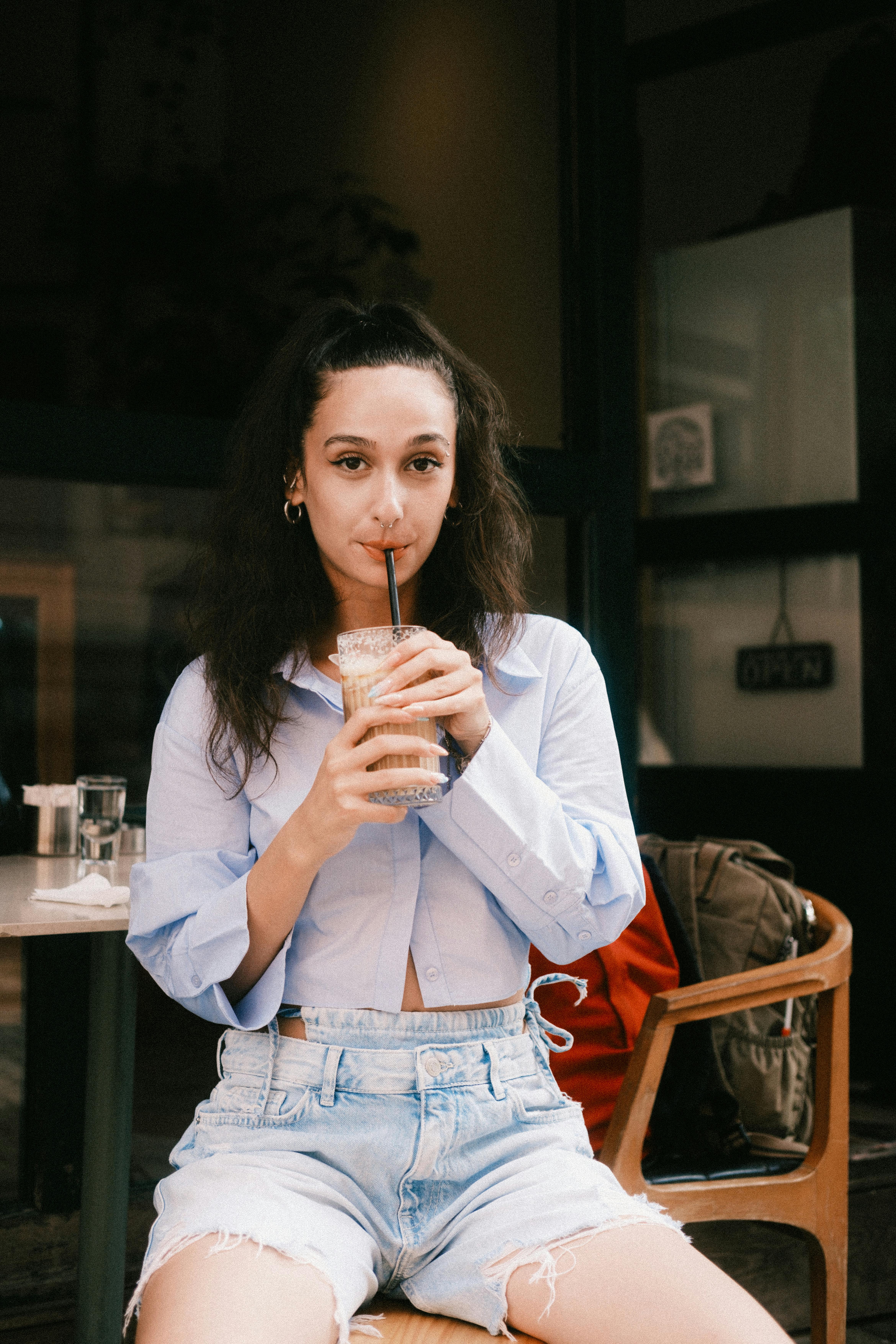 Stylish woman enjoys iced coffee at cozy café, embracing relaxation.