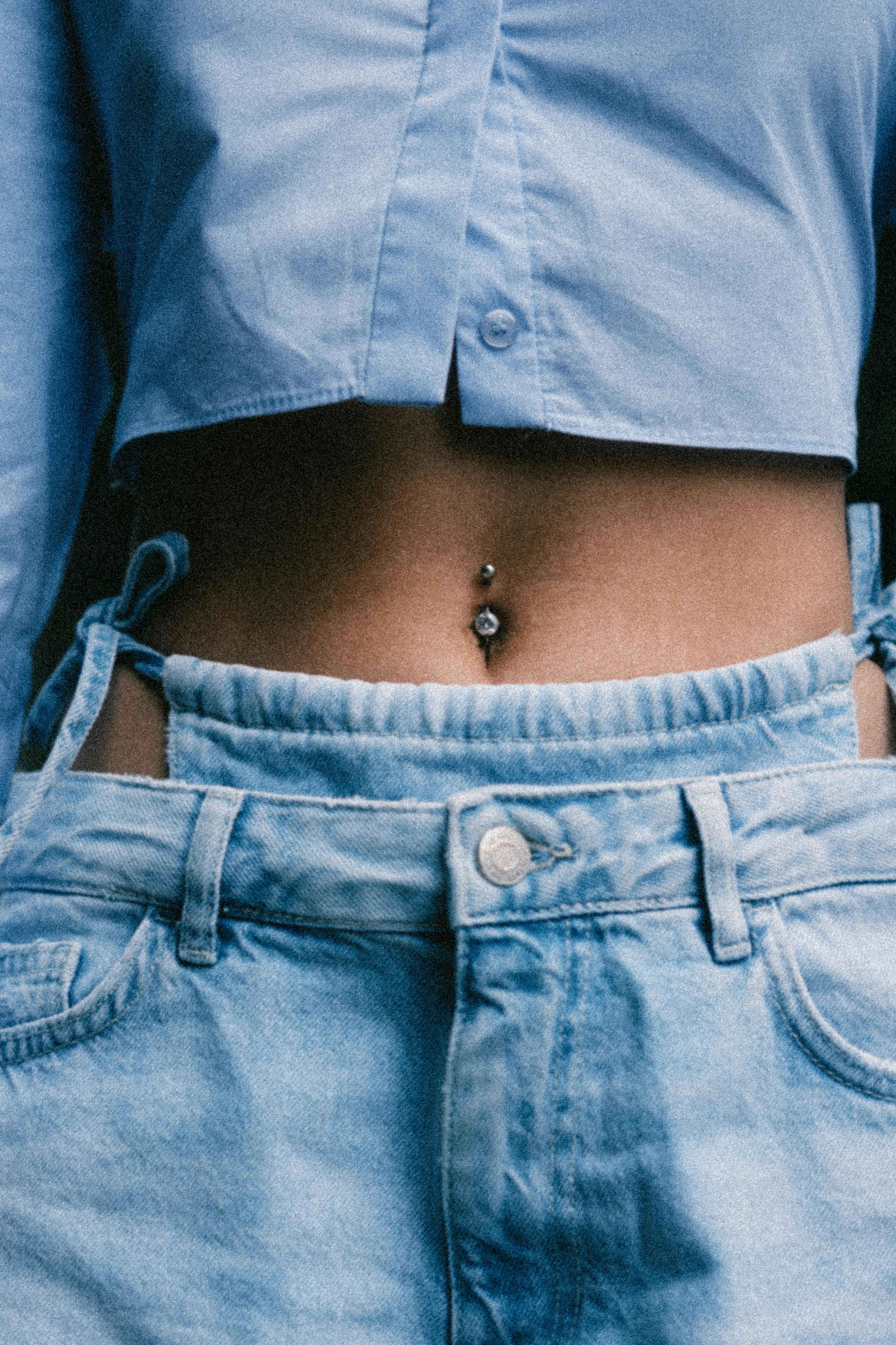 a woman with a belly piercing in her jeans