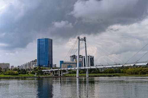 Free Striking urban landscape featuring a modern suspension bridge and tall buildings against a cloudy sky. Stock Photo
