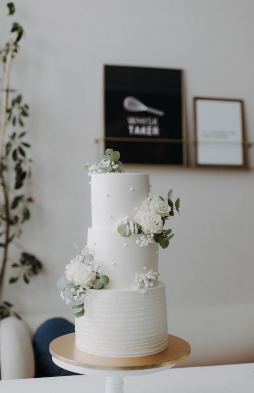 Free Three-tiered white wedding cake adorned with delicate white flowers. Stock Photo
