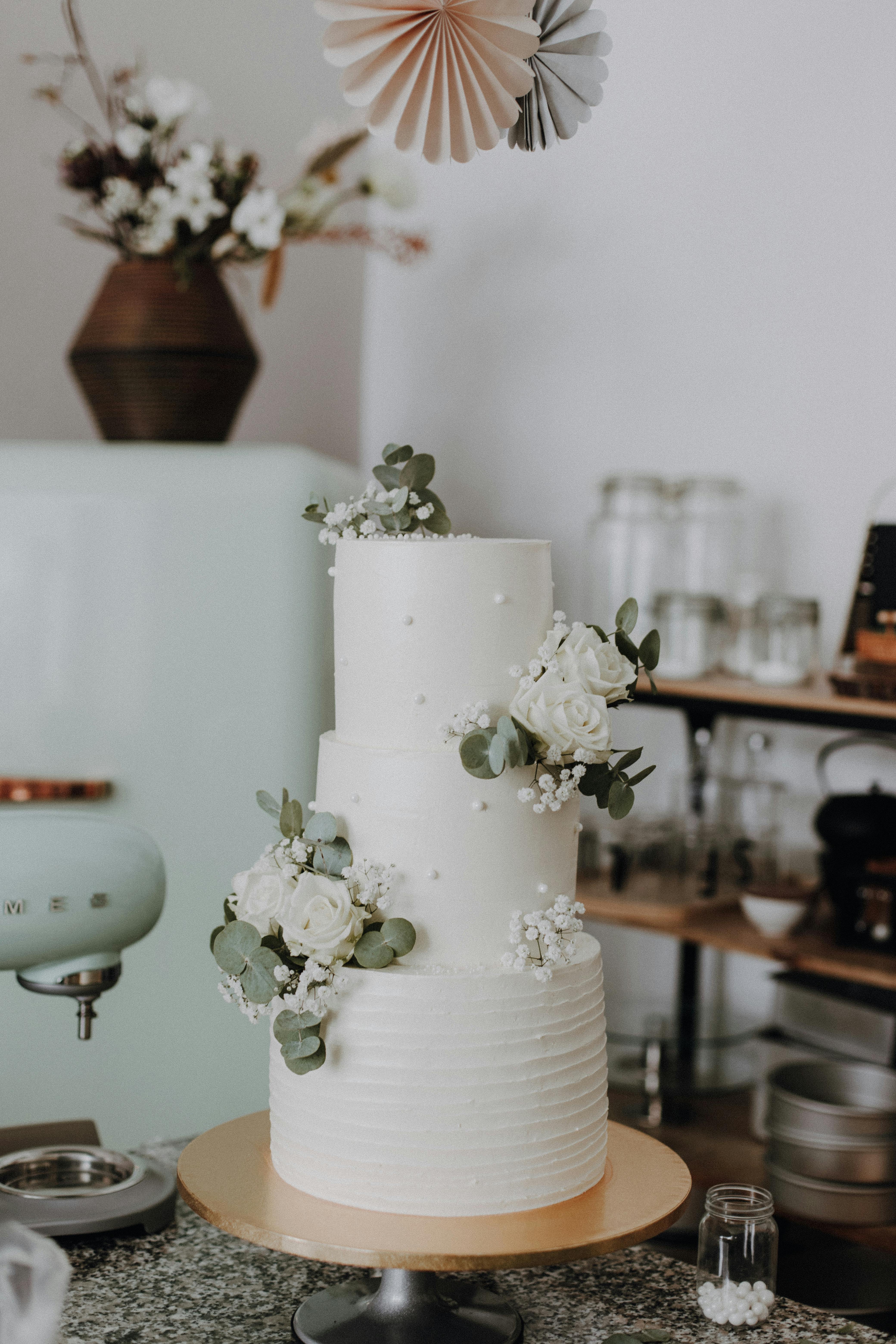 Beautiful three-tier white cake adorned with flowers in a cozy setting.