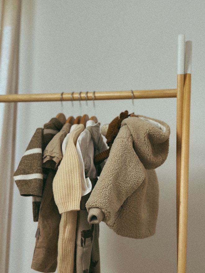 Neutral-toned children's clothing on a wooden rail — photo by Ruxanda Photography on Pexels