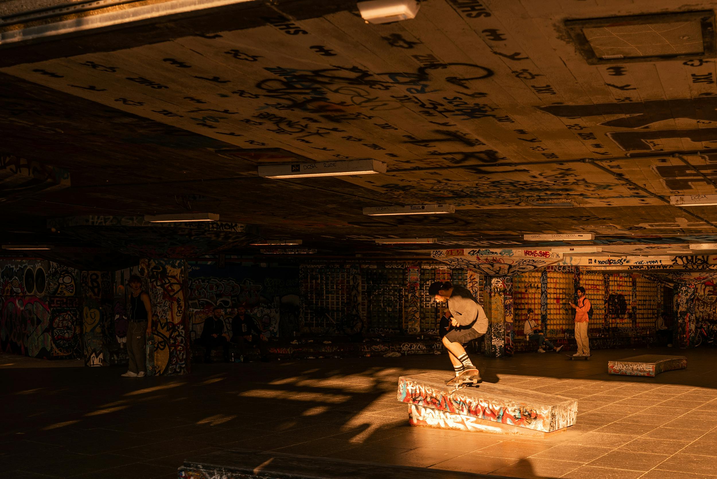 A skateboarder performs a trick in London's Southbank skatepark, filled with vibrant graffiti art.