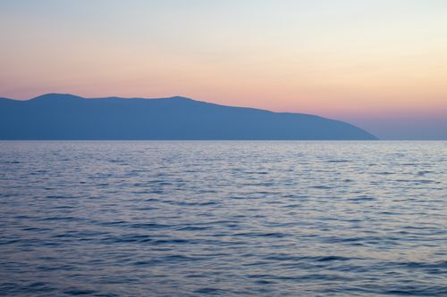 Free Captivating sunset view over the calm sea and distant mountains in Vlora, Albania. Stock Photo