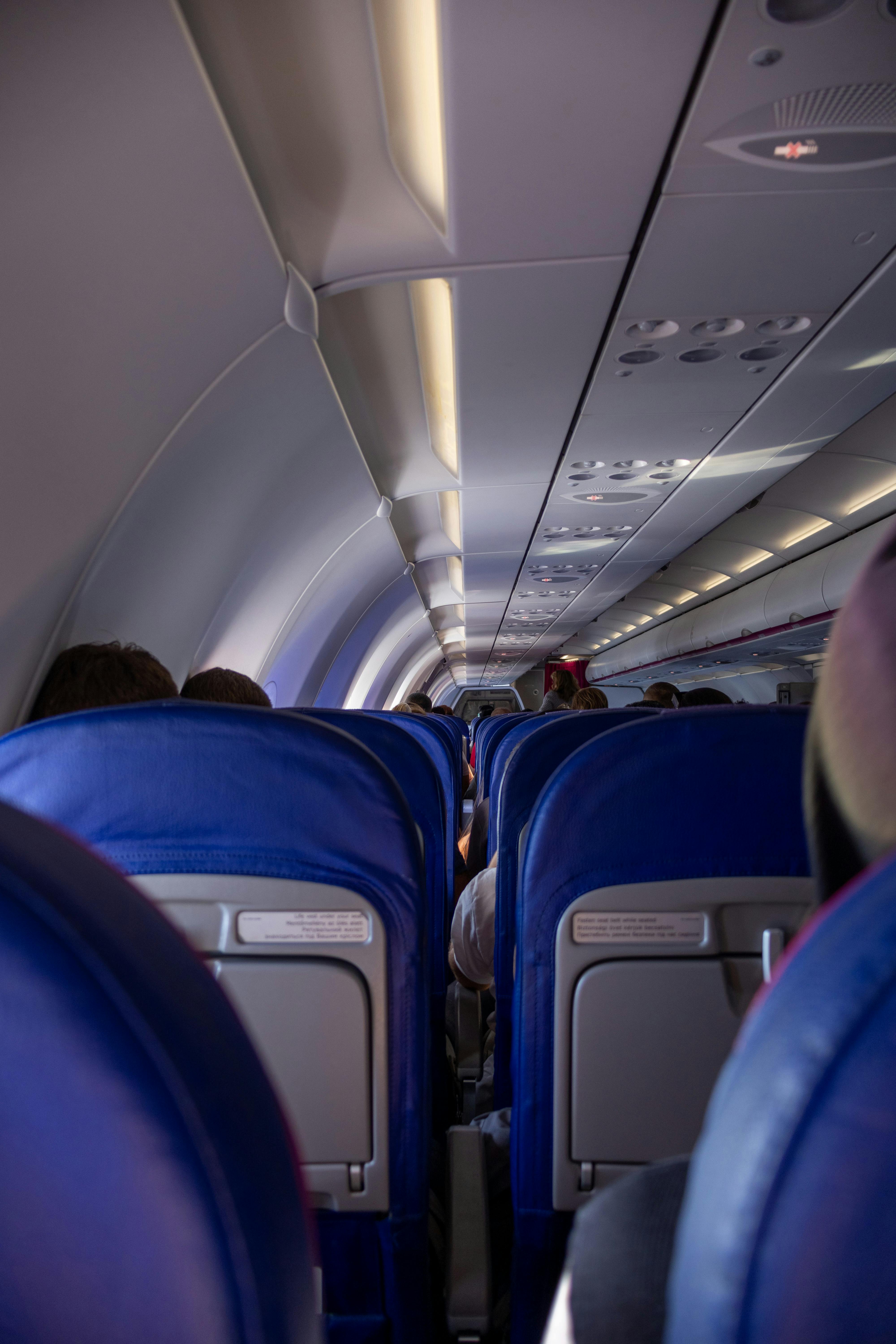Interior view of an airplane cabin showing blue seats and passengers during flight.