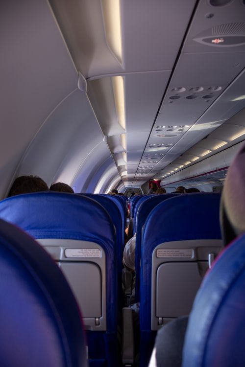 Free Interior view of an airplane cabin showing blue seats and passengers during flight. Stock Photo
