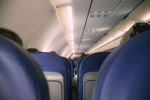Free A view of a modern airplane cabin showing rows of blue seats and overhead compartments. Stock Photo