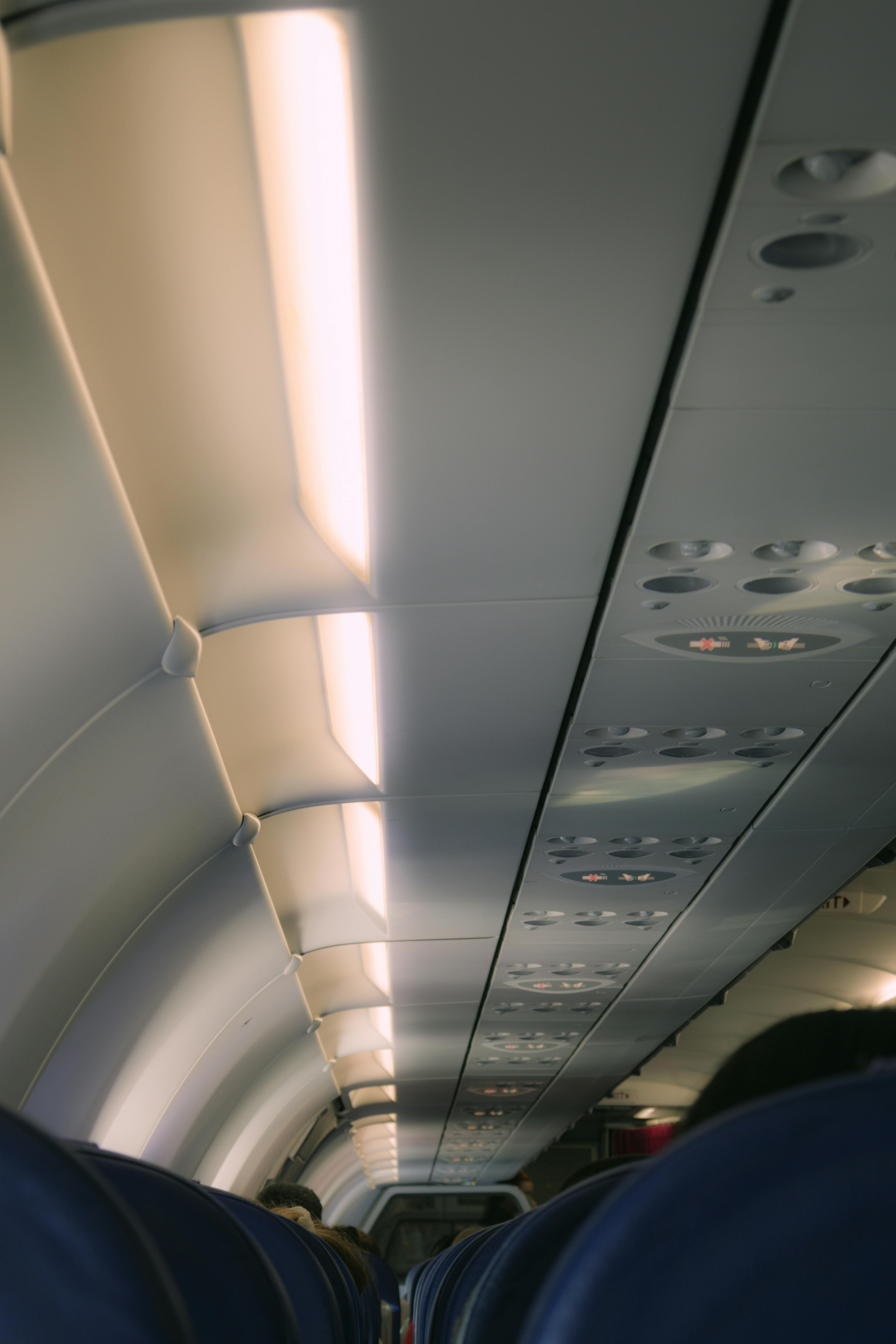 View of airplane interior aisle with overhead lighting and seats, showing modern travel environment.