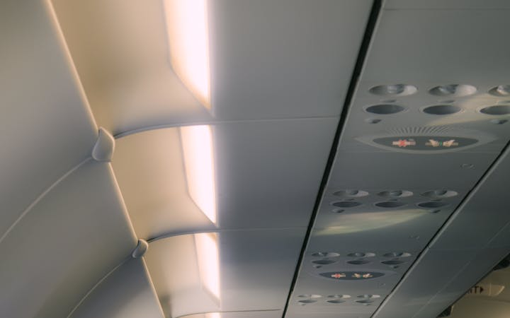 View of airplane interior aisle with overhead lighting and seats, showing modern travel environment.