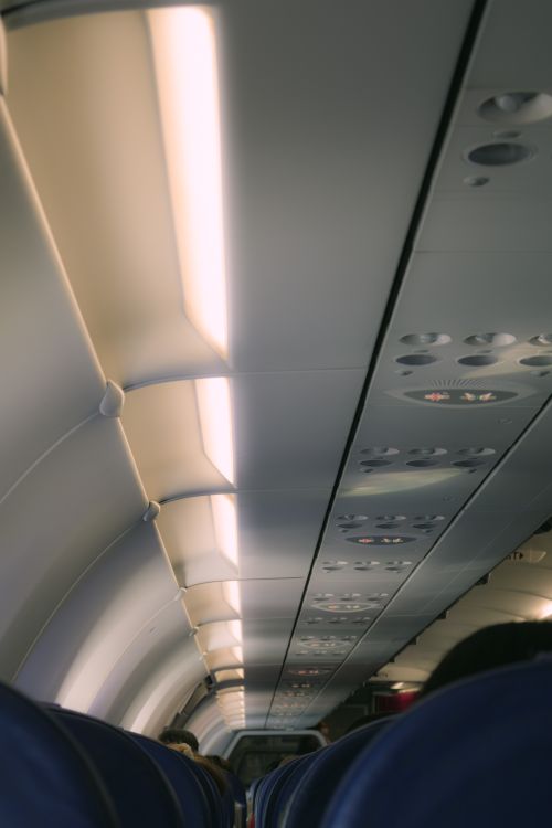 Free View of airplane interior aisle with overhead lighting and seats, showing modern travel environment. Stock Photo