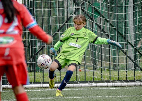 Young soccer goalie in action during a youth match, capturing a dynamic play.