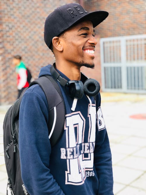 Man Wearing Black Cap, Blue Hoodie and Backpack 