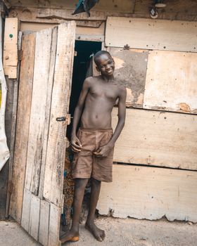 Portrait of a young man standing outside a rustic wooden hut, smiling.