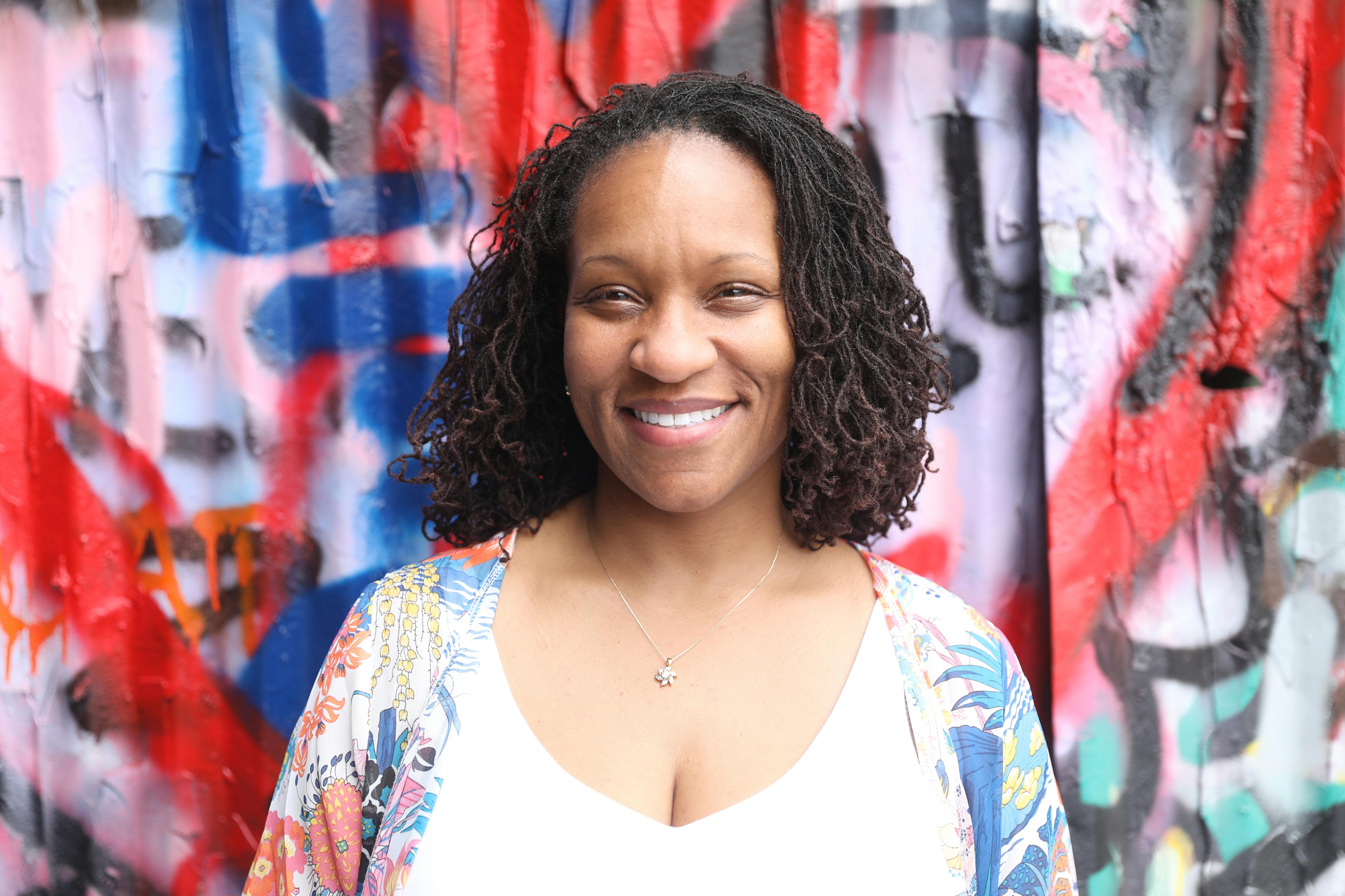 a woman standing in front of a graffiti wall