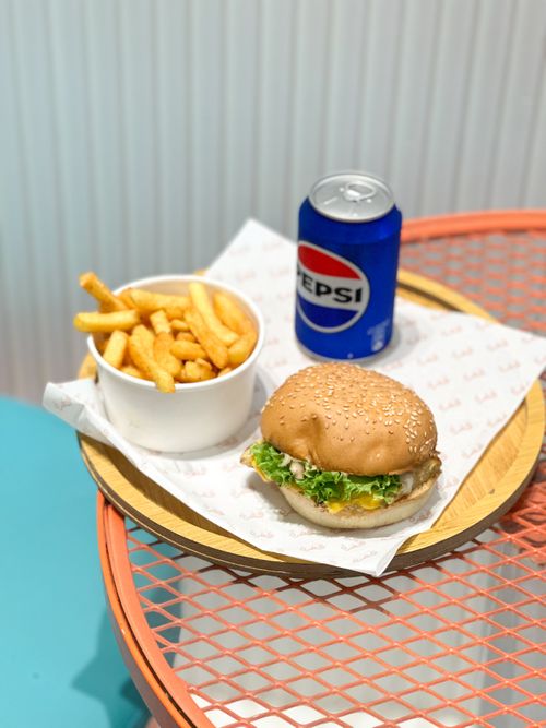 Free A delicious cheeseburger with fries and a can of soda on a vibrant tabletop. Stock Photo
