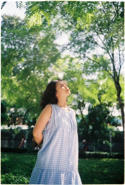 Free A woman enjoys a moment of peace under the trees in a sunlit park. Stock Photo
