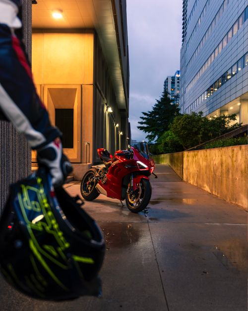 Free A vibrant red motorcycle parked in an urban alley at dusk, capturing the spirit of adventure and speed. Stock Photo