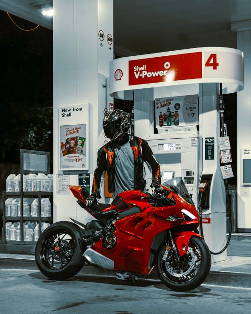 Free A motorcyclist refuels a red Ducati bike at a modern gas station at night. Stock Photo
