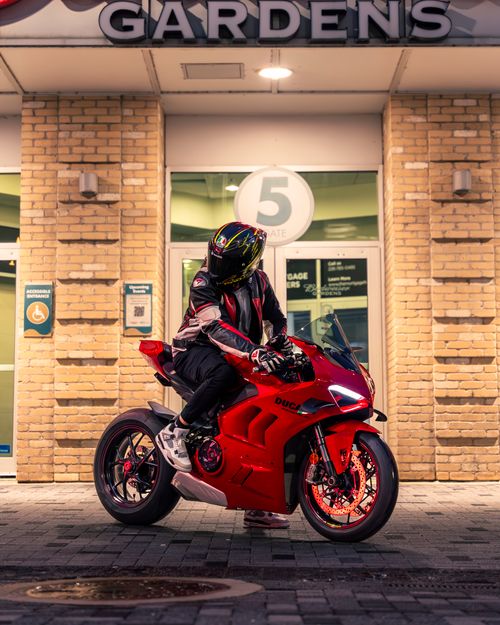 Free A motorcyclist on a Ducati in a city at night, parked outside a building. Stock Photo