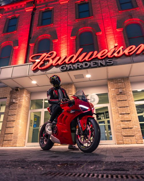 Free A rider on a red motorcycle in front of Budweiser Gardens at night with vivid lighting. Stock Photo