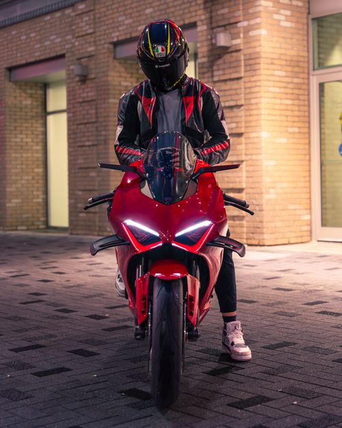 Free A motorcyclist in protective gear rides a Ducati sport bike in a city environment at night. Stock Photo