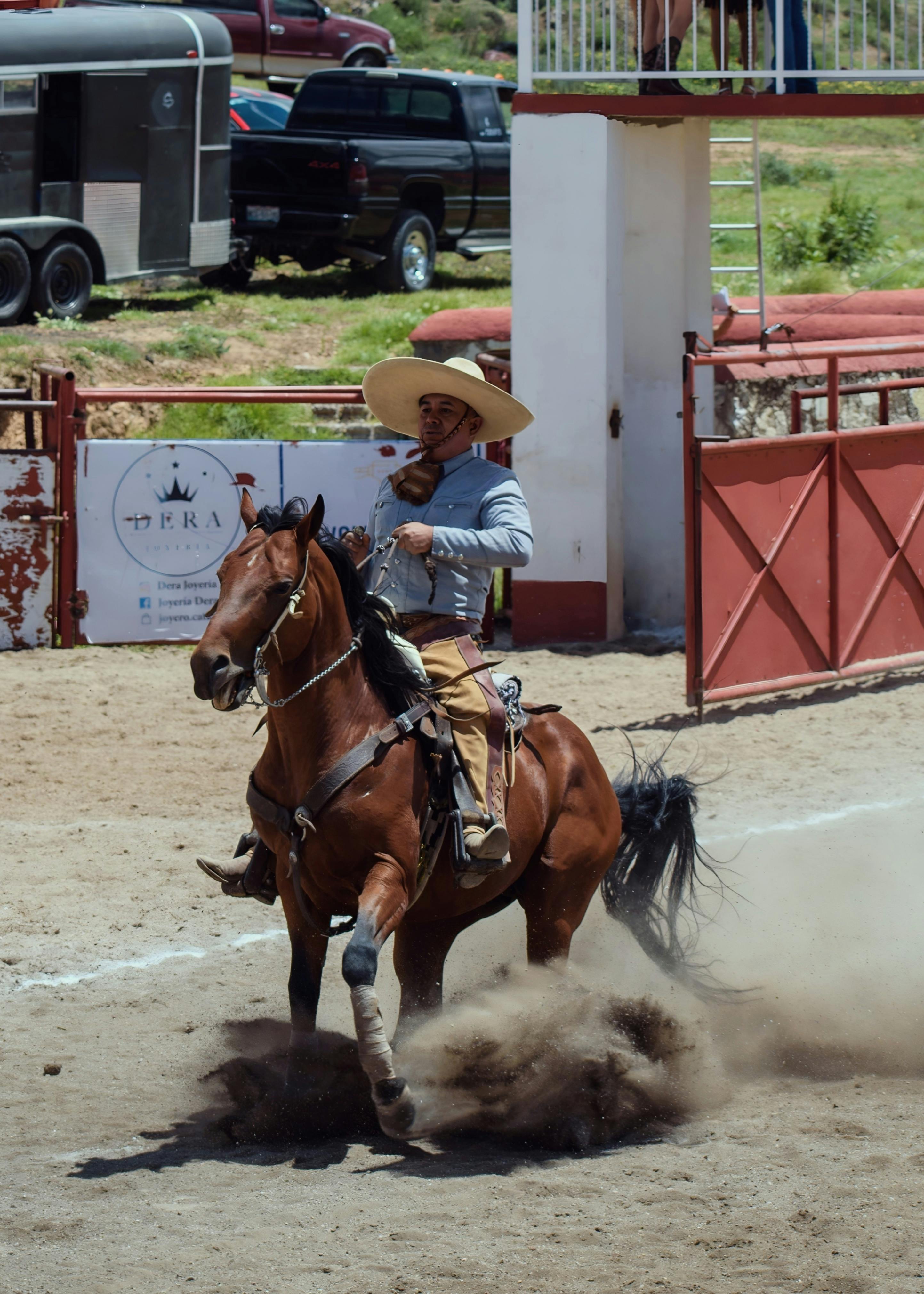 Charro in traditional attire performing in a rodeo arena with a horse.