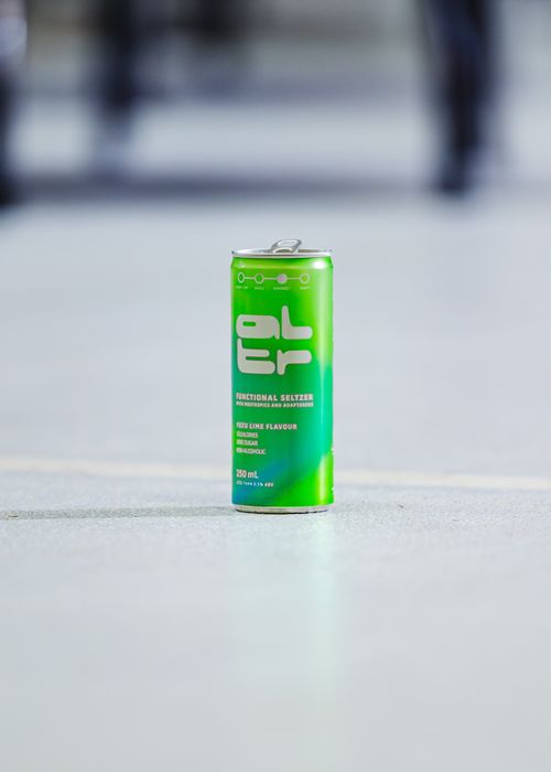 Free Close-up of a green energy drink can on pavement with blurred background outdoors. Stock Photo