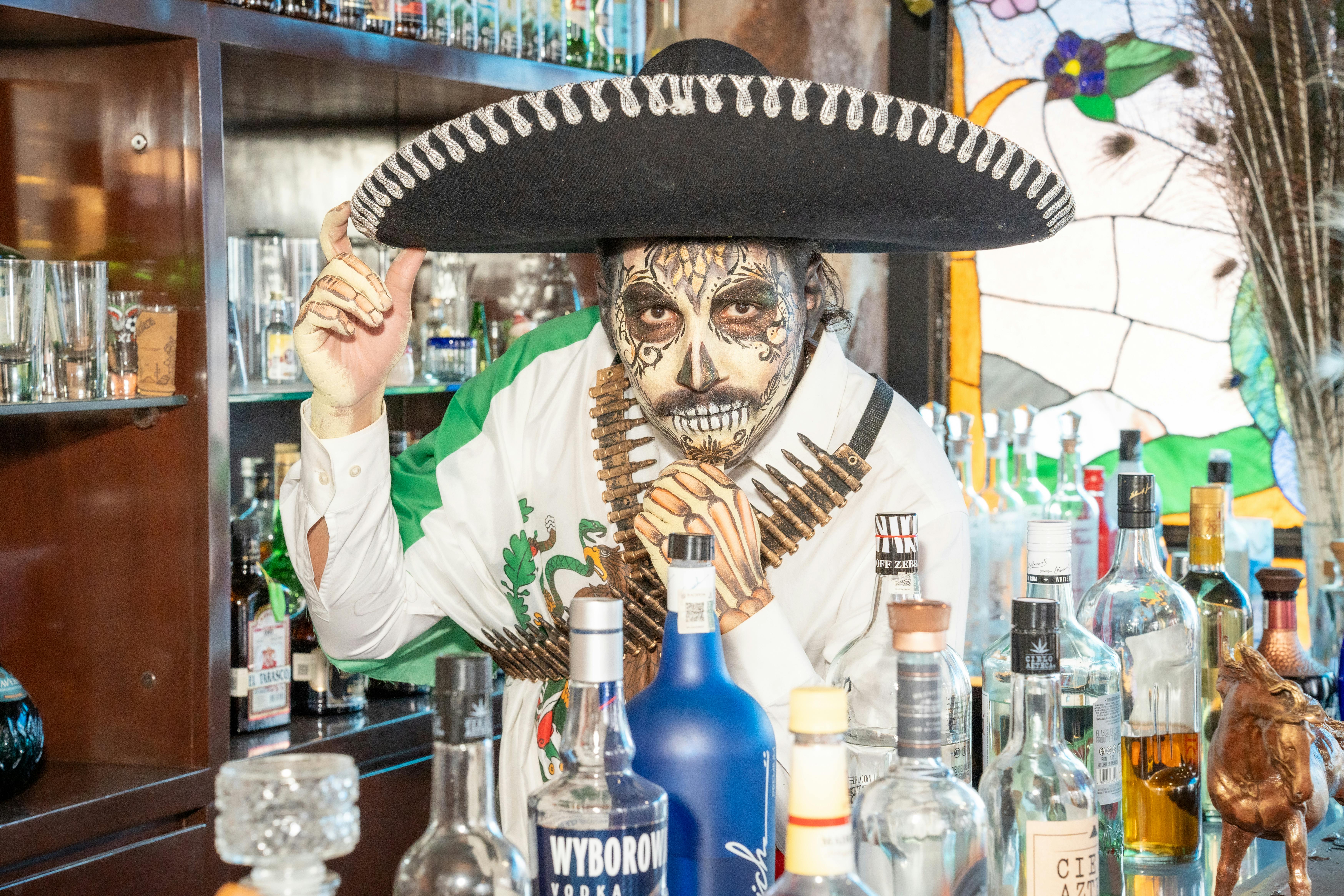 a man in a mexican costume behind the bar