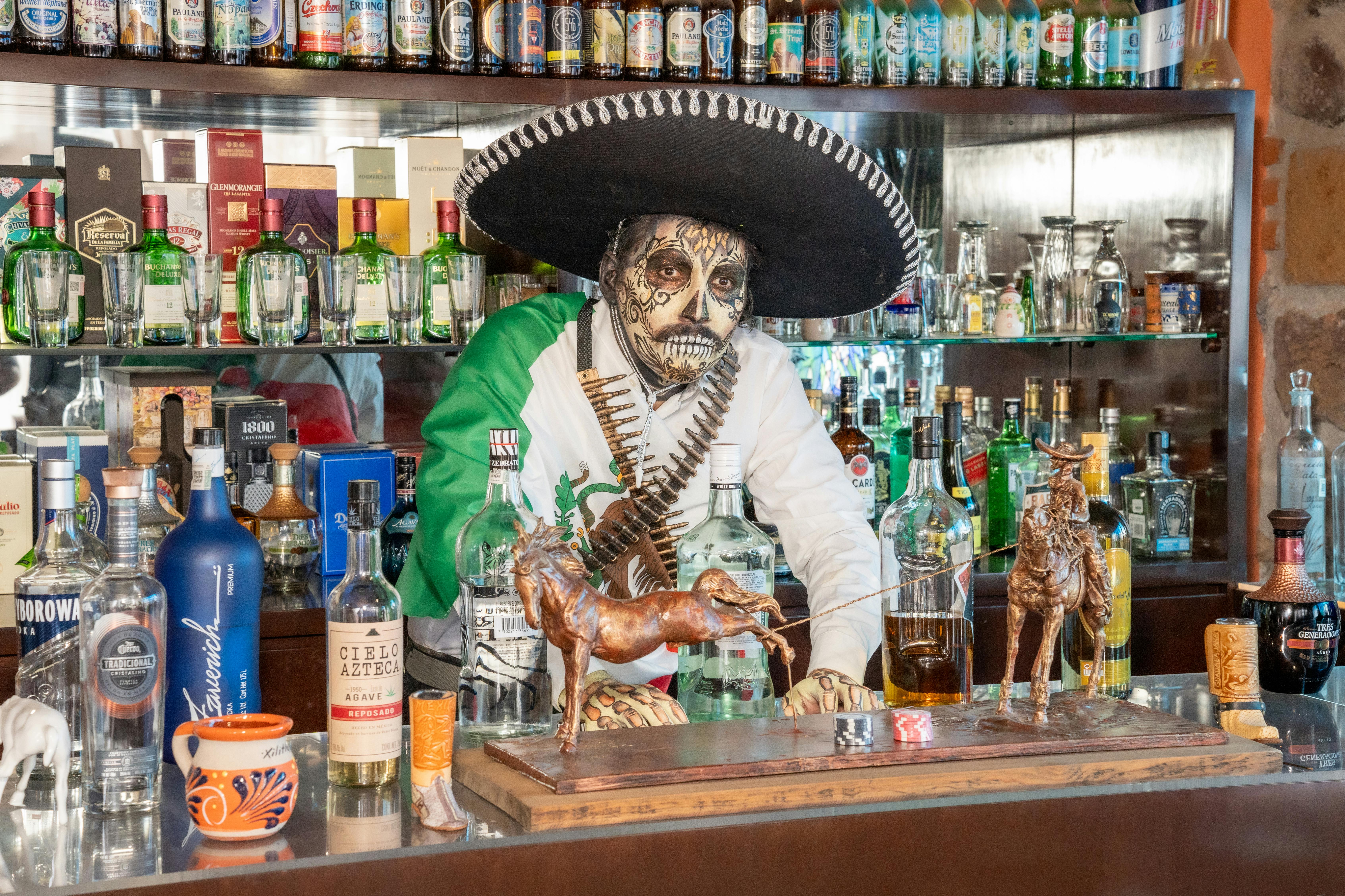 a mexican man in a sombrero is behind the bar