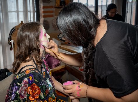 A woman paints a girl's face for Día de los Muertos in Mexico City.