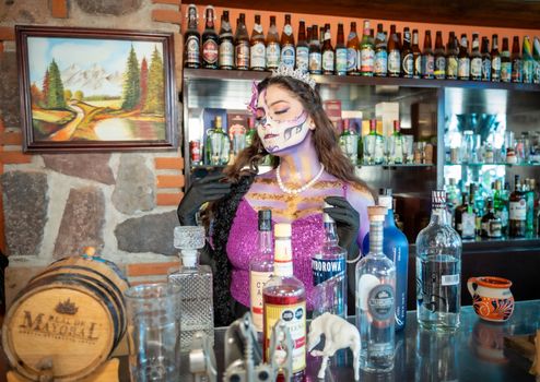 A festive bar scene in CDMX featuring a woman painted as La Calavera Catrina.
