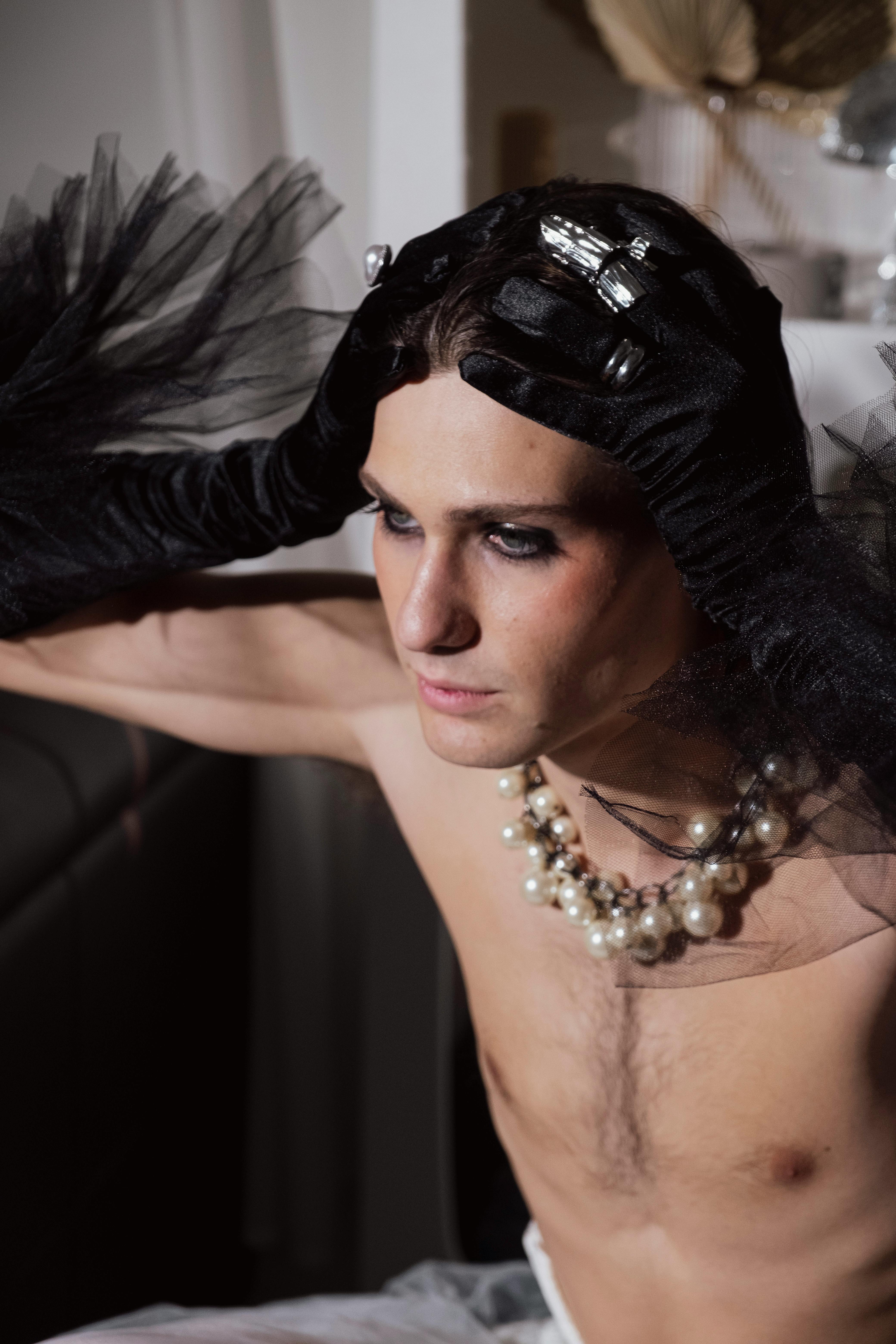 a shirtless man with black gloves and jewelry