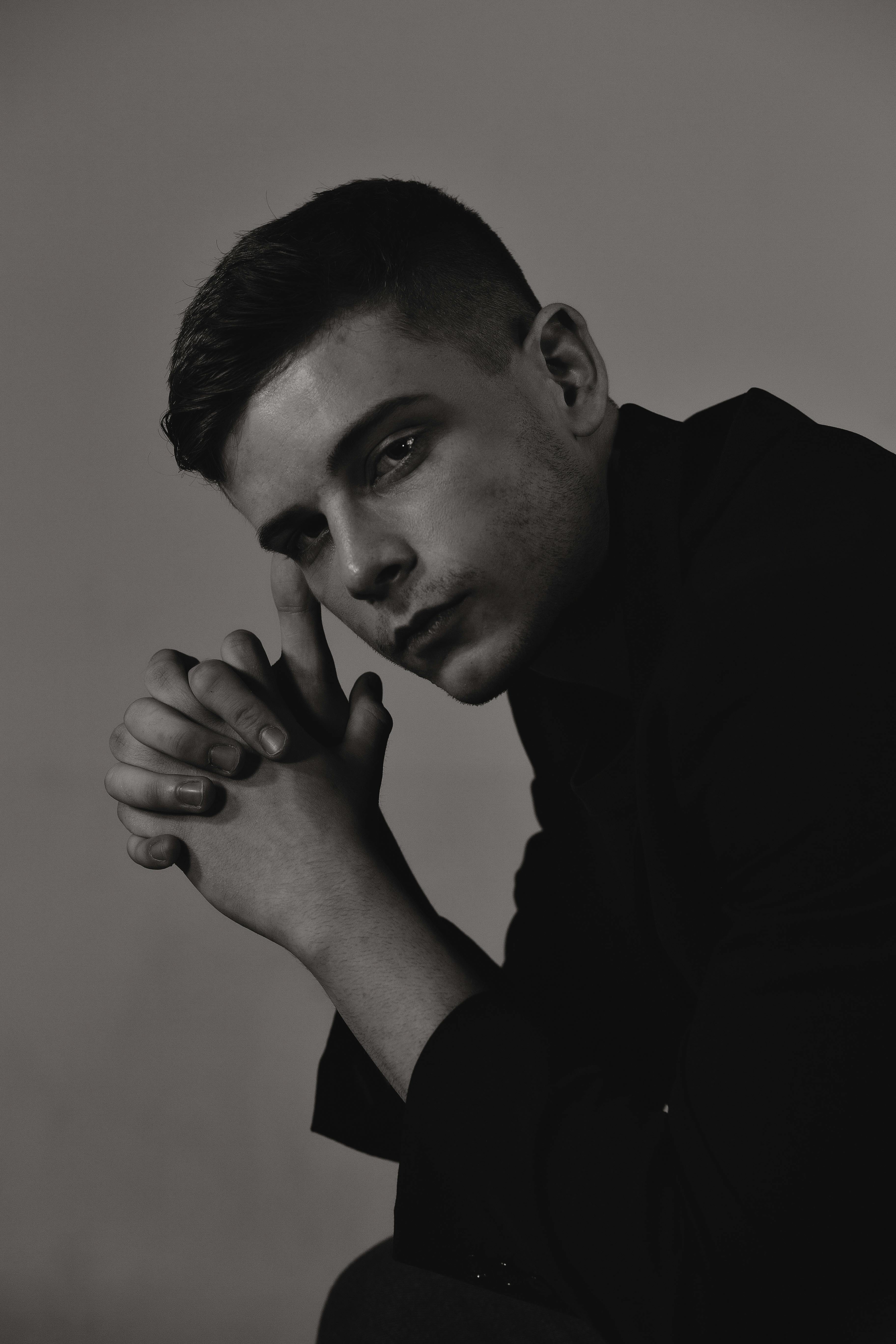Moody black and white portrait of a man deep in thought, shot in a studio.