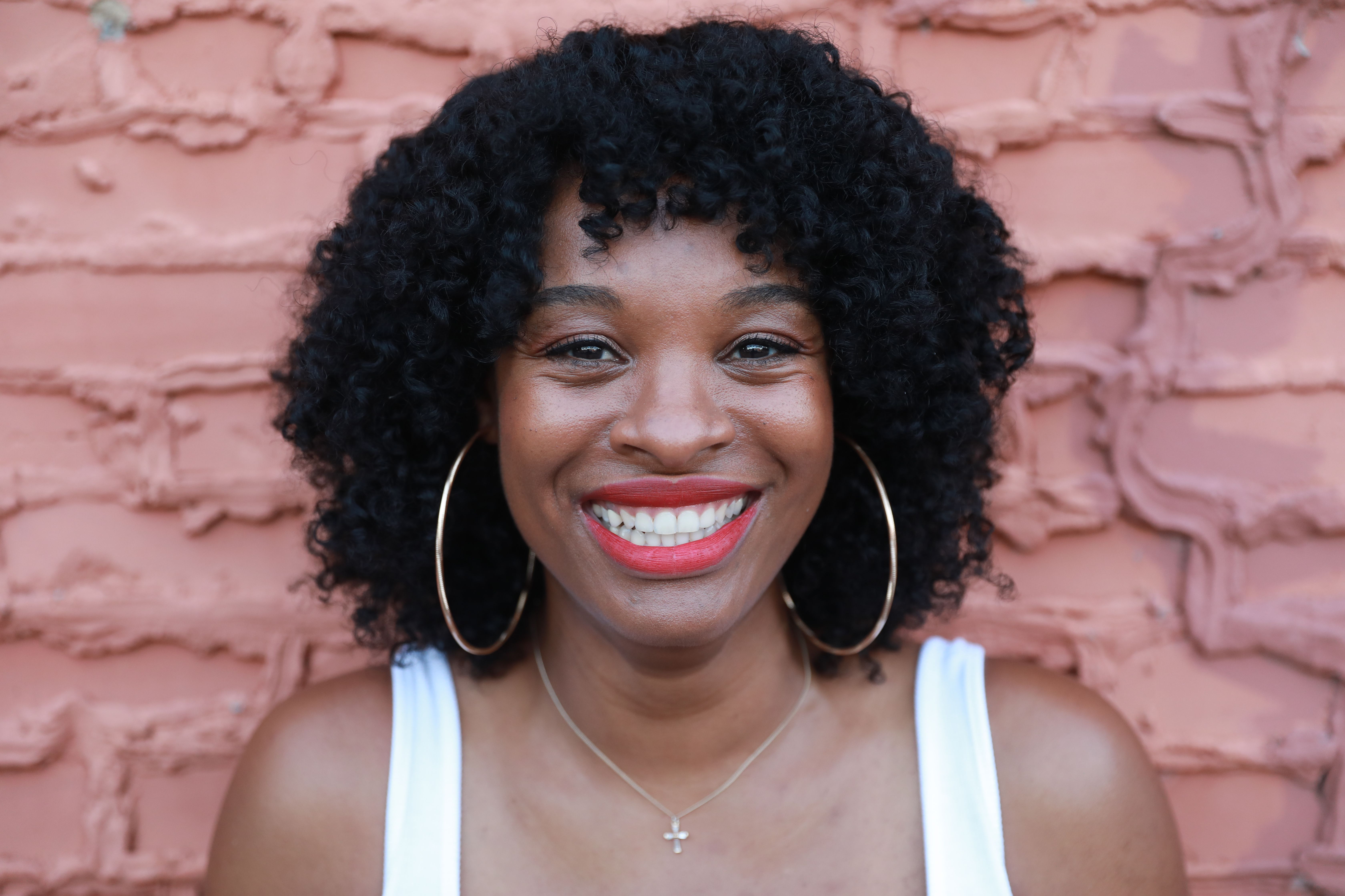 A smiling woman with curly hair and earrings · Free Stock Photo