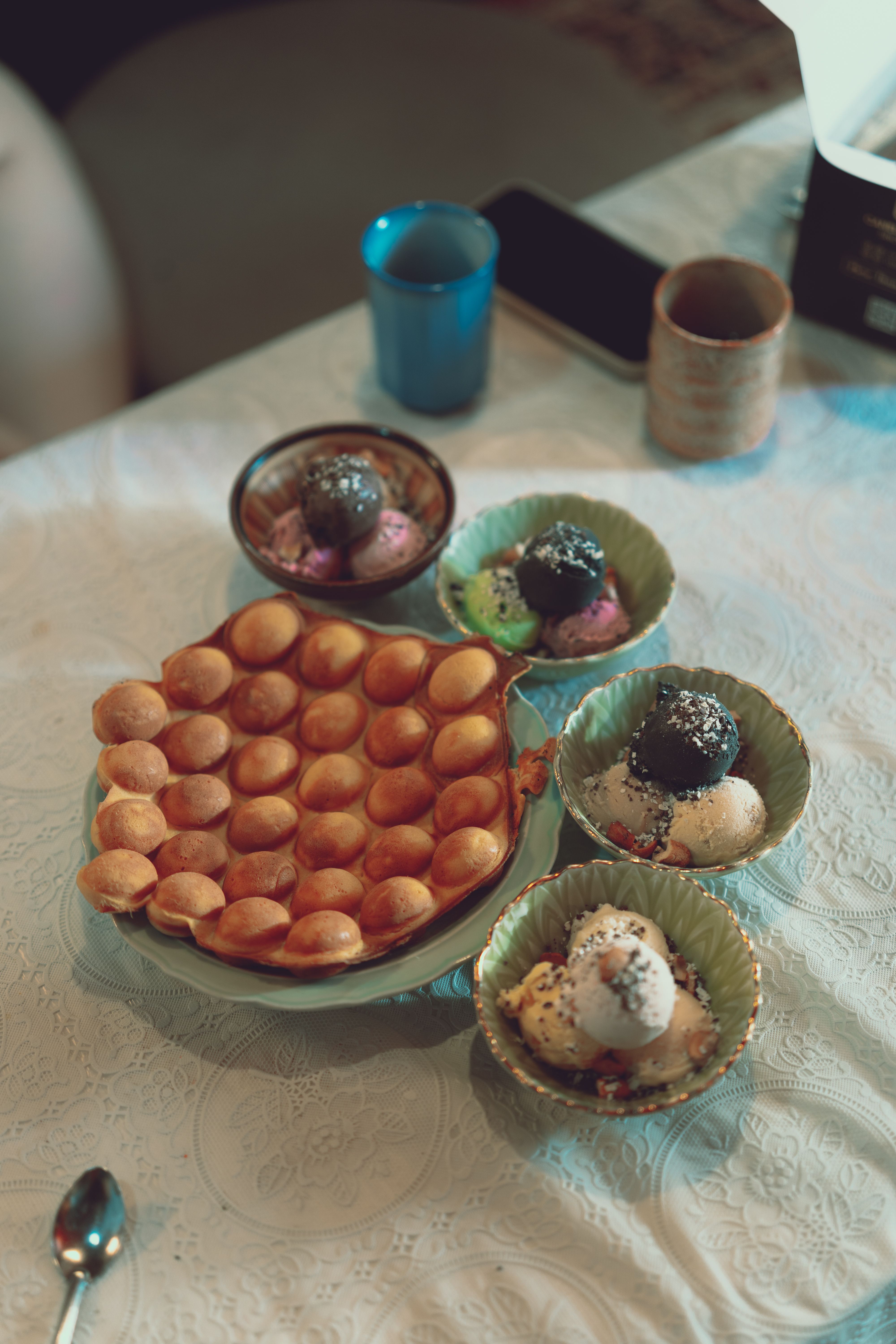 A delectable spread featuring waffles and assorted ice cream scoops on a patterned tablecloth.