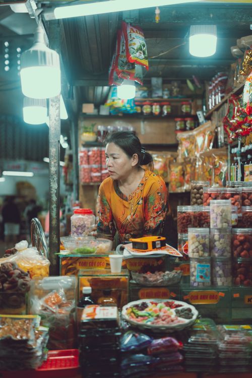 Free Vietnamese vendor at a vibrant market stall in Dalat, showcasing local goods and foods. Stock Photo