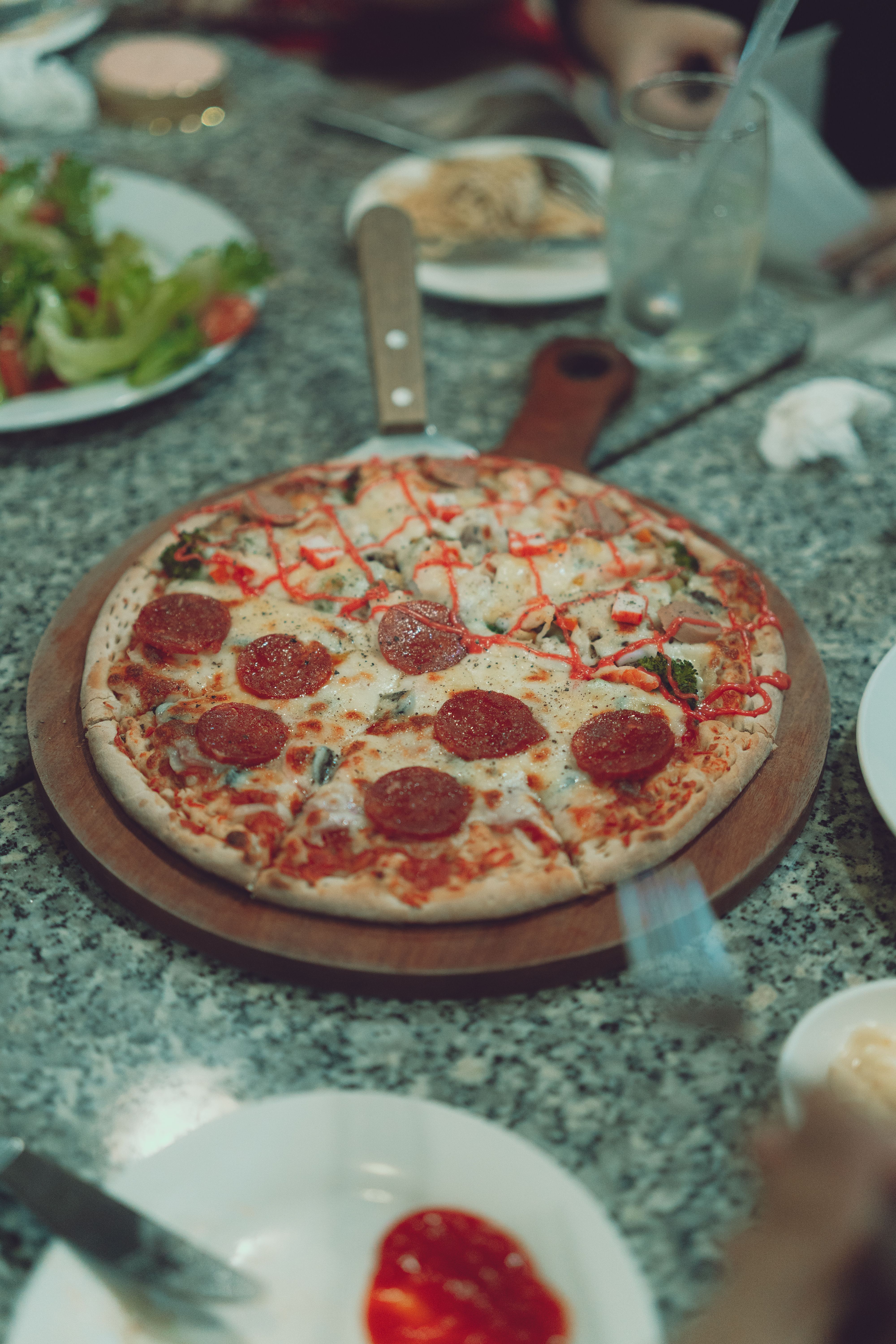 Freshly baked pepperoni pizza served on a marble table, captured in Dalat, Vietnam.