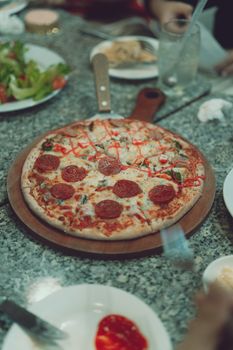 Freshly baked pepperoni pizza served on a marble table, captured in Dalat, Vietnam.