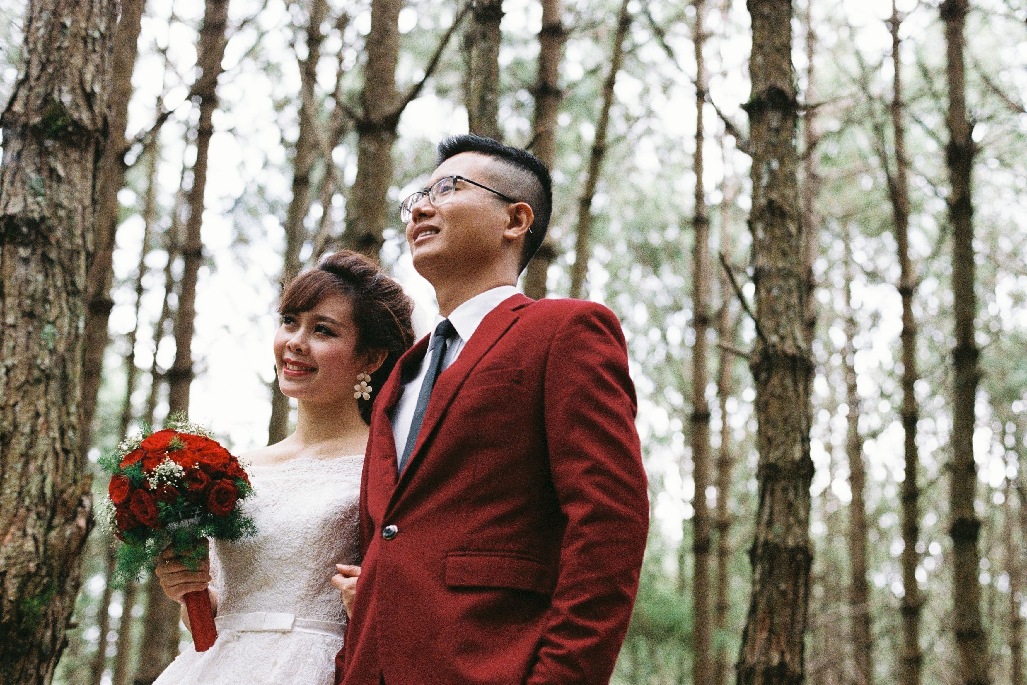A bride and groom standing in the woods · Free Stock Photo