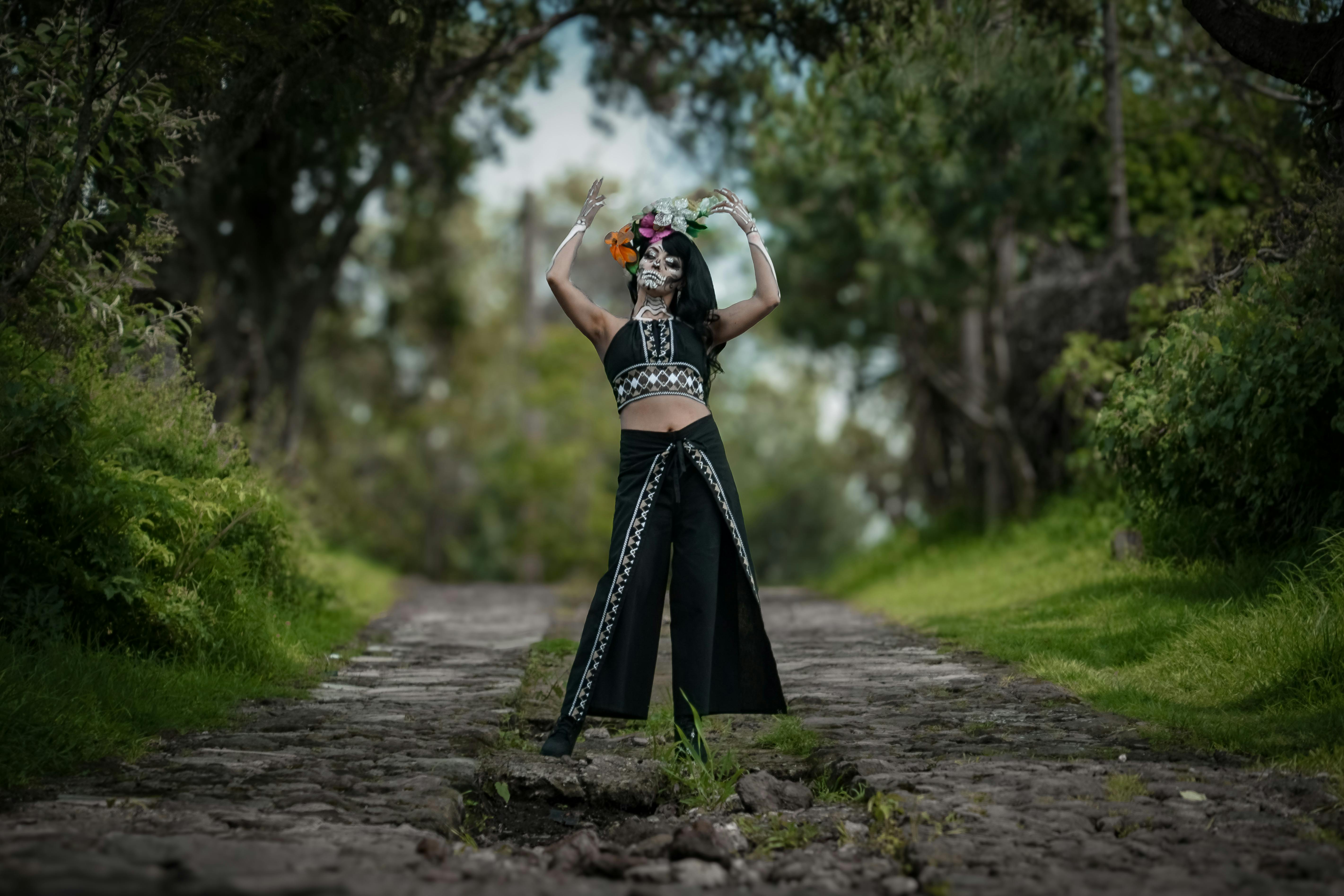 a woman in a black and white dress is standing on a road