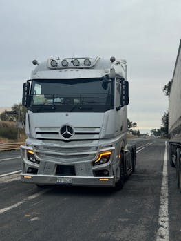 A sleek white truck travels along a highway, showcasing modern transportation.