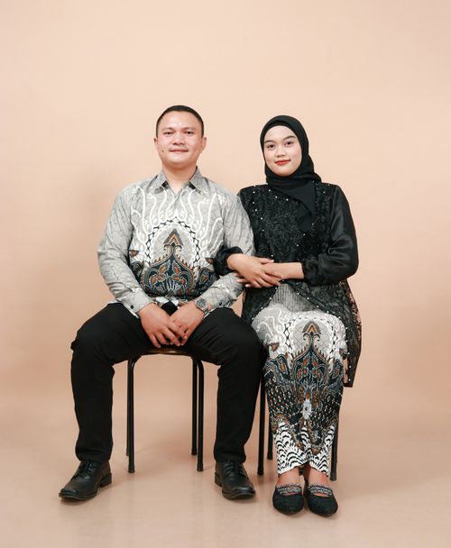 Free A couple dressed in matching traditional outfits posing for a studio portrait. Stock Photo