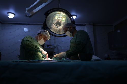Free Two surgeons in a dimly lit operating room in Idlib, Syria, perform a surgical procedure. Stock Photo