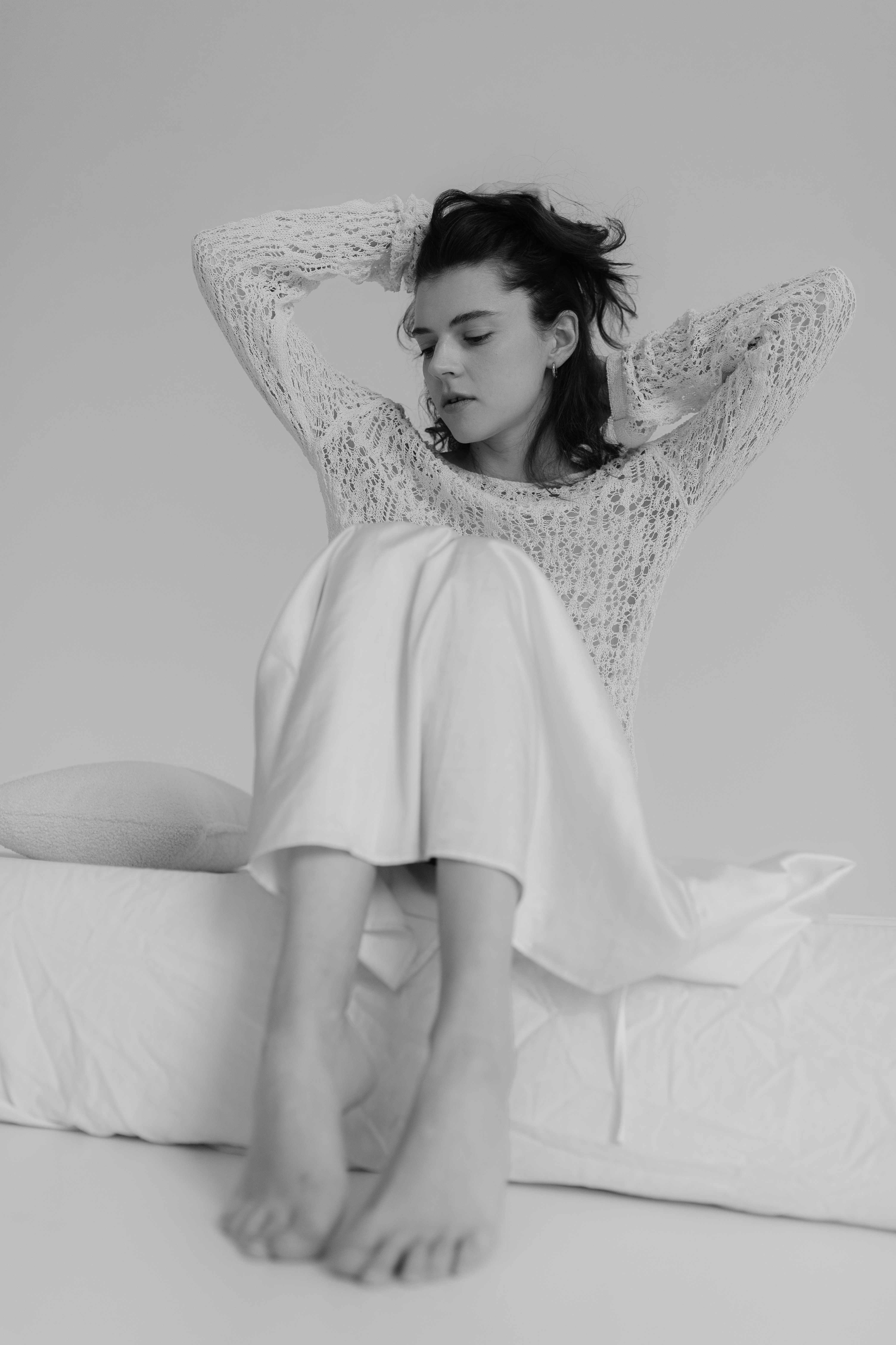 A woman in a white sweater sitting on a bed · Free Stock Photo