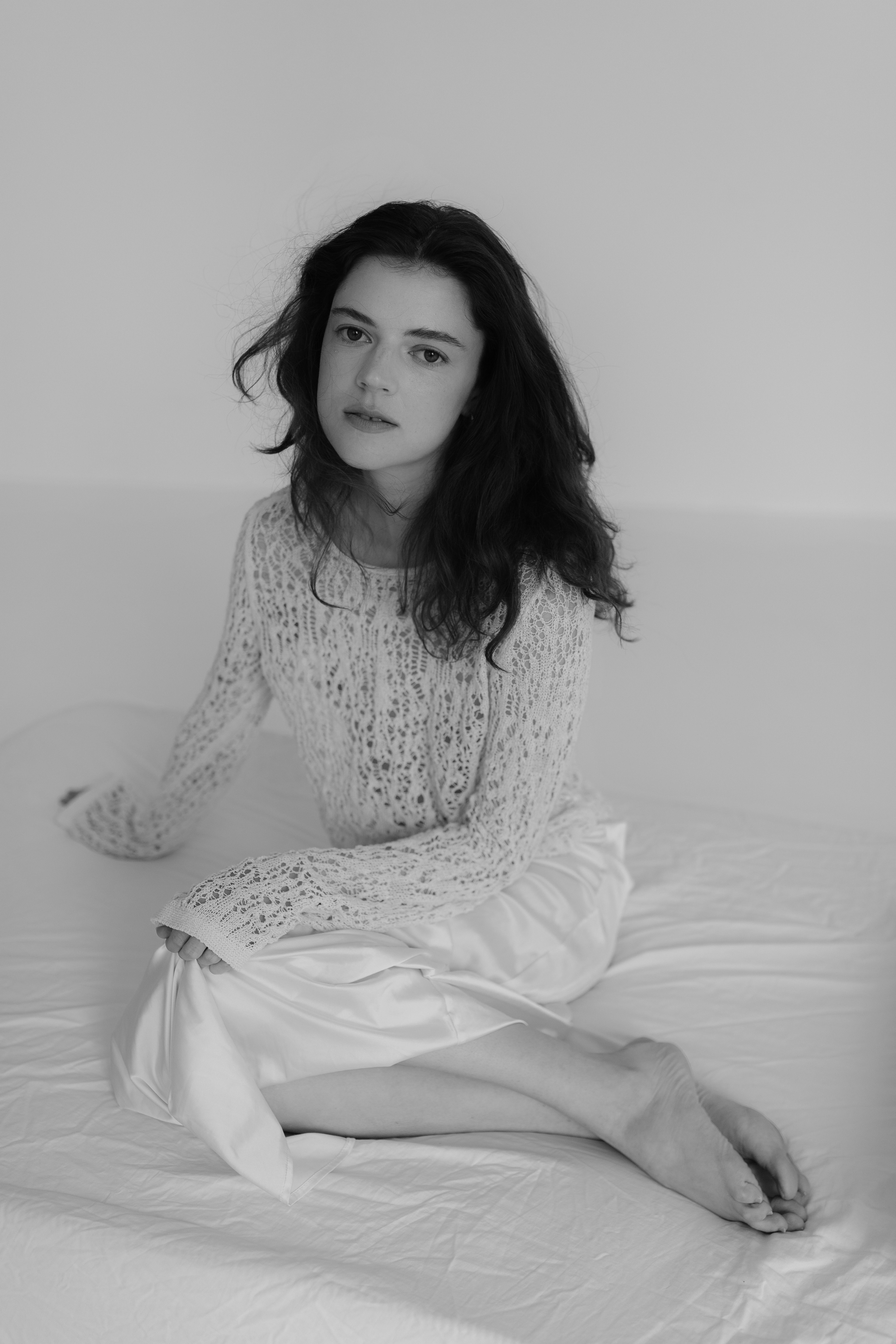 A woman in a white sweater sitting on a bed · Free Stock Photo