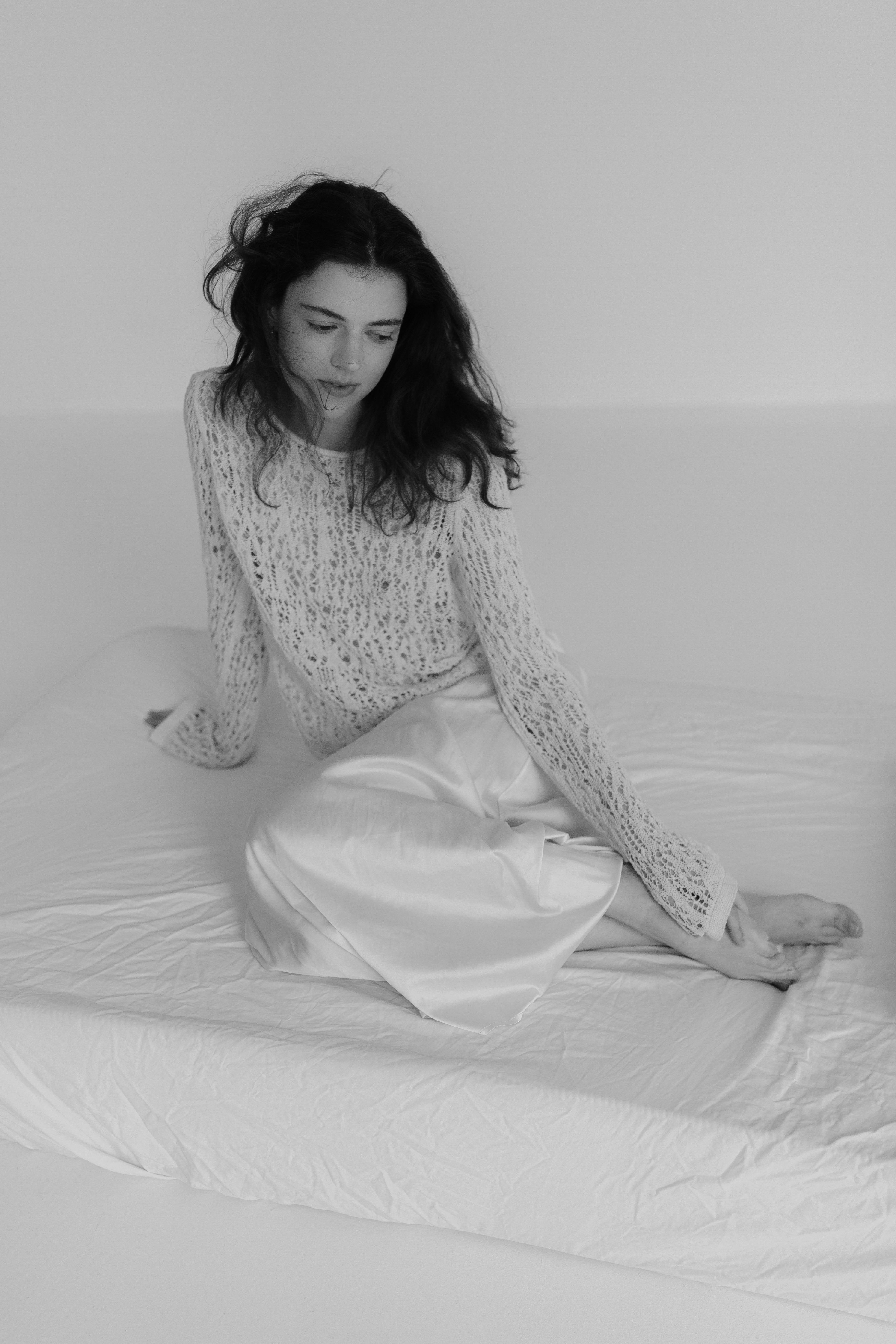 A woman in a white sweater sitting on a bed · Free Stock Photo