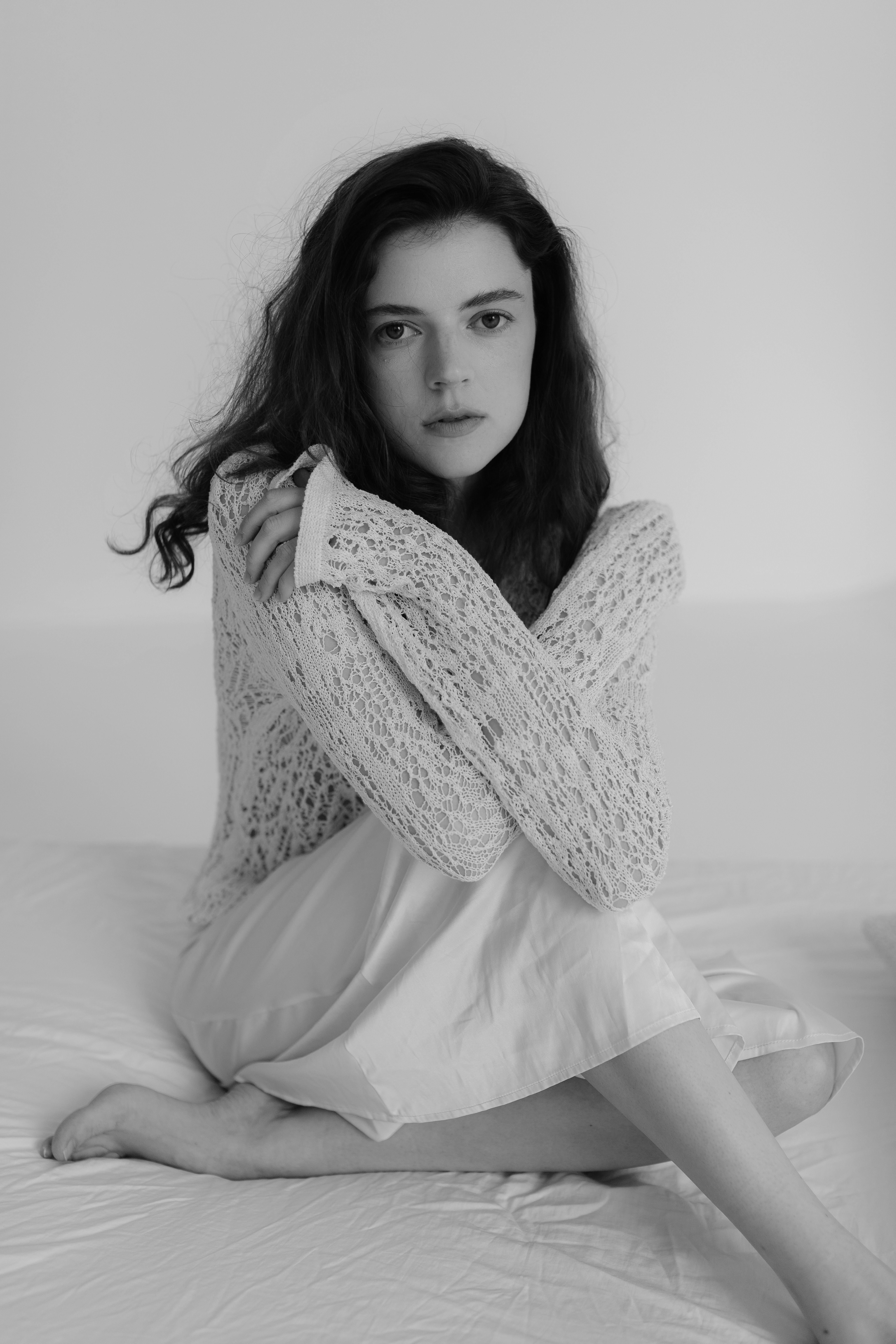 A woman in a sweater sitting on a bed · Free Stock Photo