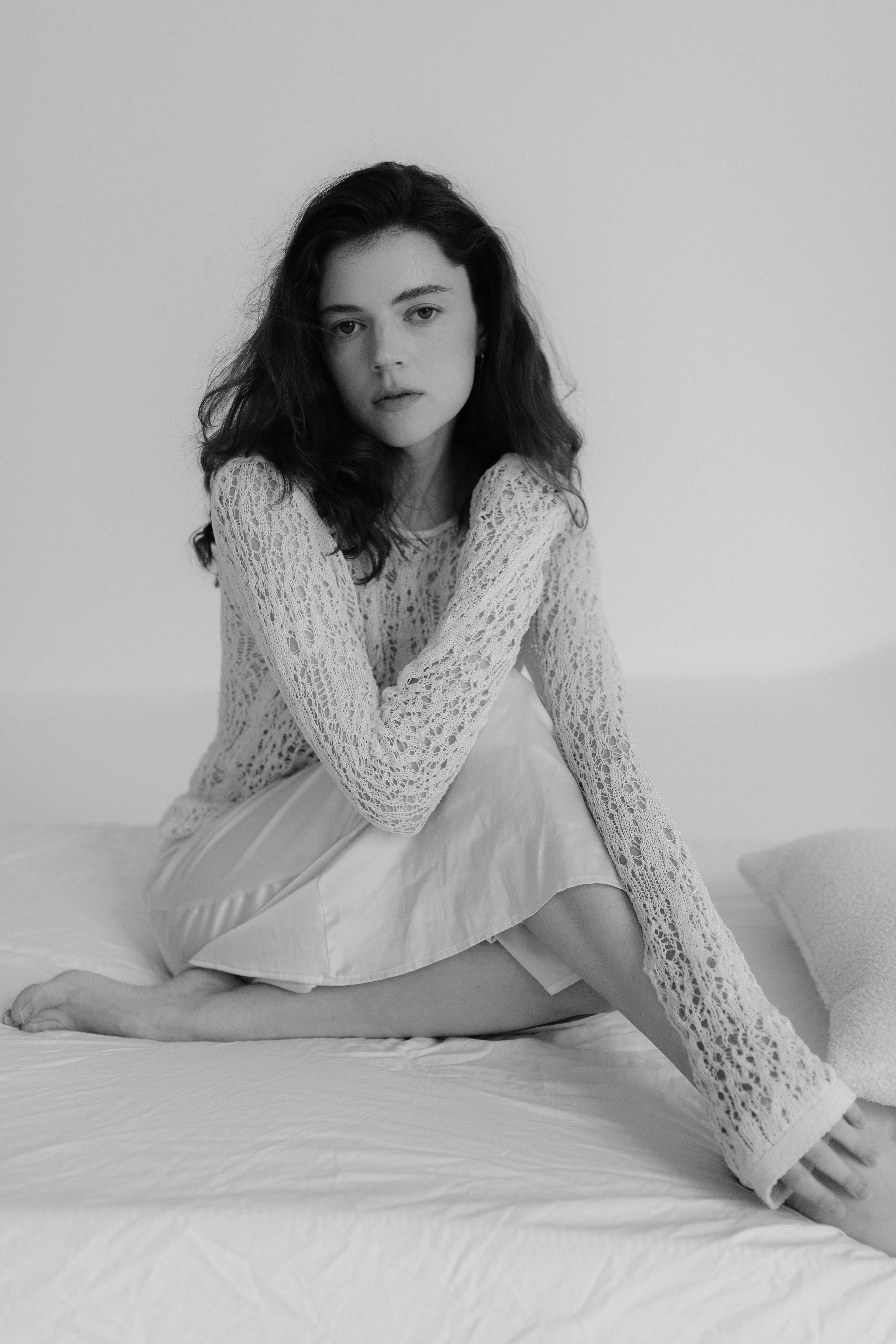 A woman in a white sweater sitting on a bed · Free Stock Photo